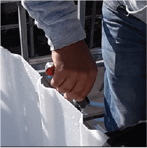  A person is using a utility knife to scrape the loose plastic from the edge of a cut container.