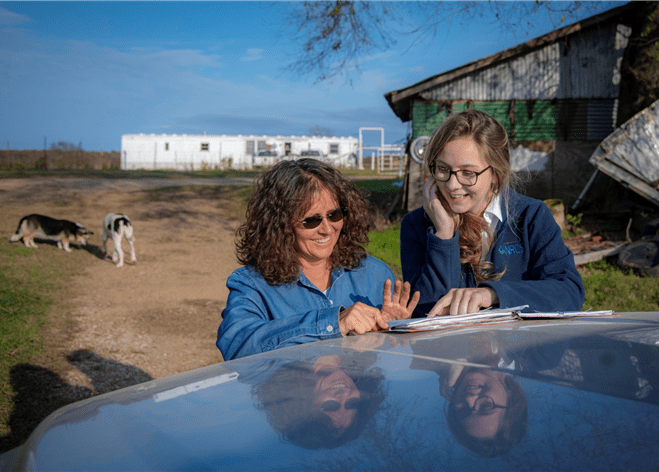 A farmer and conservation planner reviewing a conservation plan on the hood of a truck.