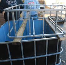 The treated lumber atop the fish tank, followed by the grow bed frame atop the treated lumber.