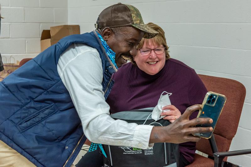 Two people smile as they take a selfie using a smartphone