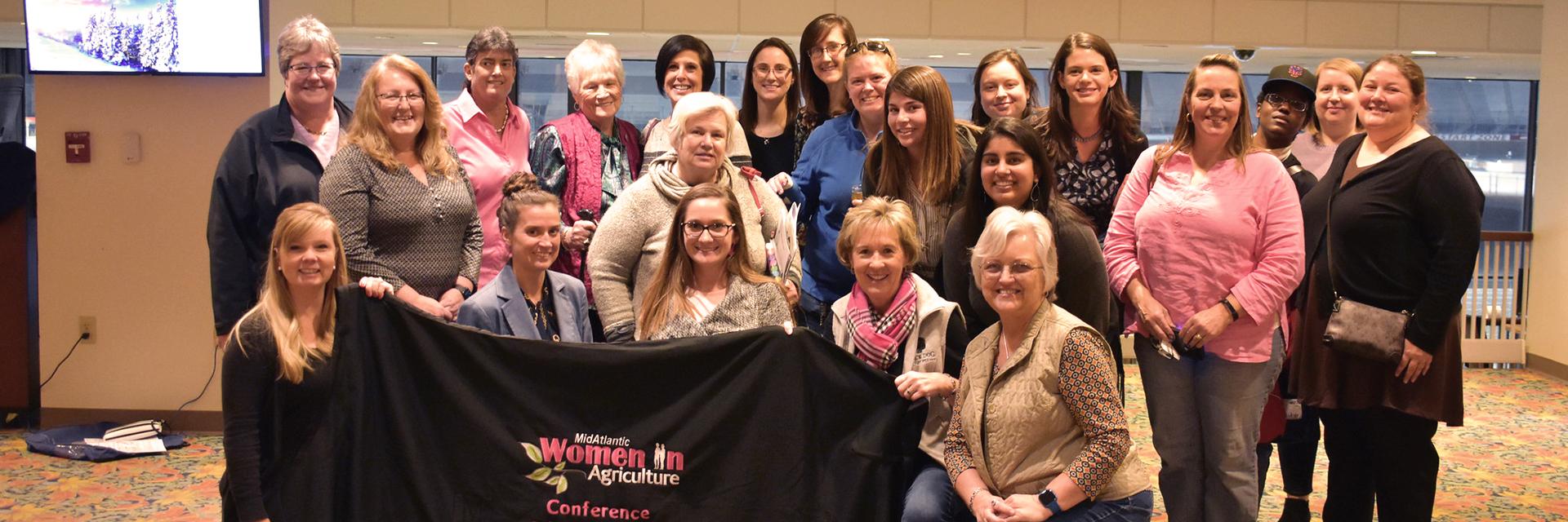 Group of women holding Women in Ag black banner in pink writing 