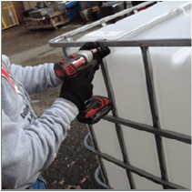 A person is removing bolts from the secured bars of an IBC.